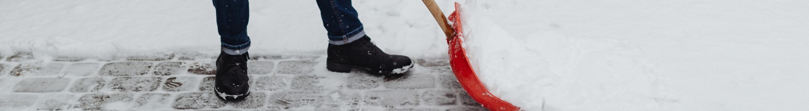 A person pushes snow with a shovel