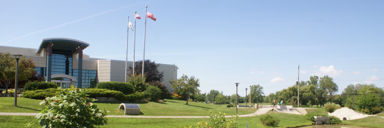 A large building surrounded by gardens and a skate park. 