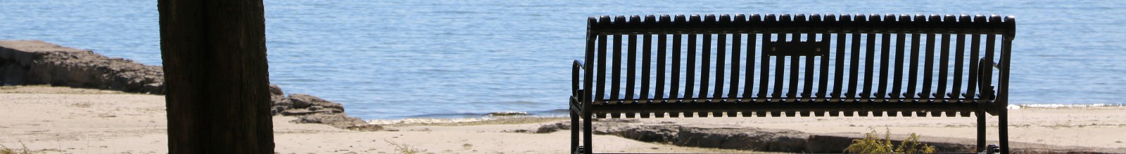 A park bench in front of the Lake Erie on a sunny day